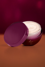 Pote de Desodorante Hidratante Corporal Perfumado Luna Intenso redondo, na cor vinho, aberto, mostrando o produto dentro, de textura cremosa branca. A tampa está ao lado do pote. Fundo vinho.