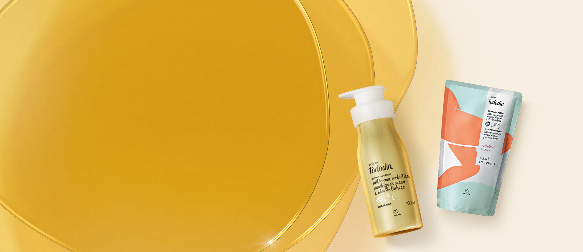 Frasco amarelo com tampa branca e sachê de refil com estampa azul e laranja de creme para o corpo Tododia Macadâmia em fundo em tons de amarelo.