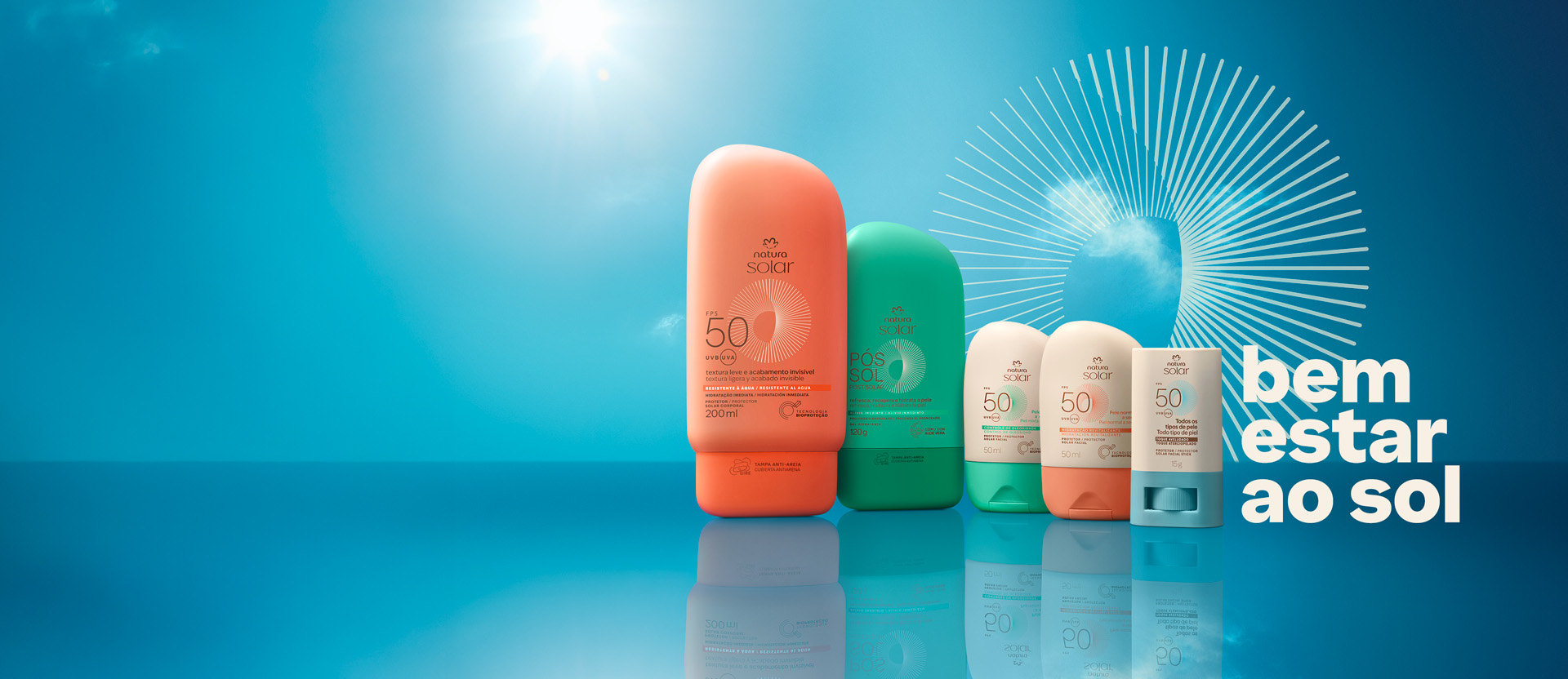 Embalagens Natura Solar Corporal FPS 50 em laranja, Pós-Sol em verde, Faciais FPS 50 pele mista em creme e verde e pele normal em creme e laranja e Stick Facial FPS 50 creme e azul, com texto “bem estar ao sol”, sobre céu azul com grafismo.