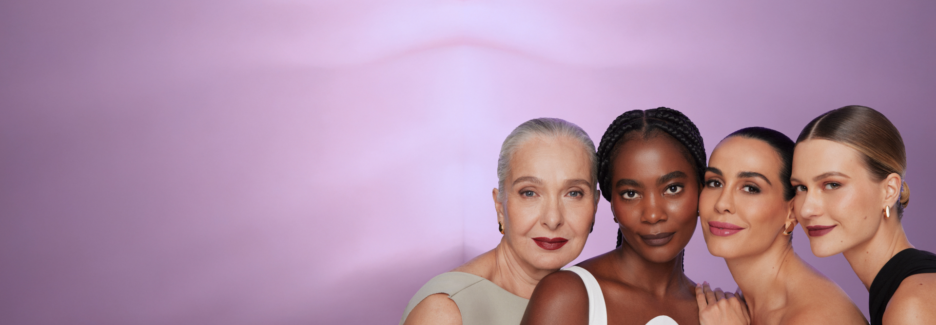 Foto de 4 modelos de diferentes idades. Todas elas estão com cabelo preso, leve sorriso no rosto, usando sombra, blush nas bochechas e batom. Fundo da imagem em degradê lilás.
