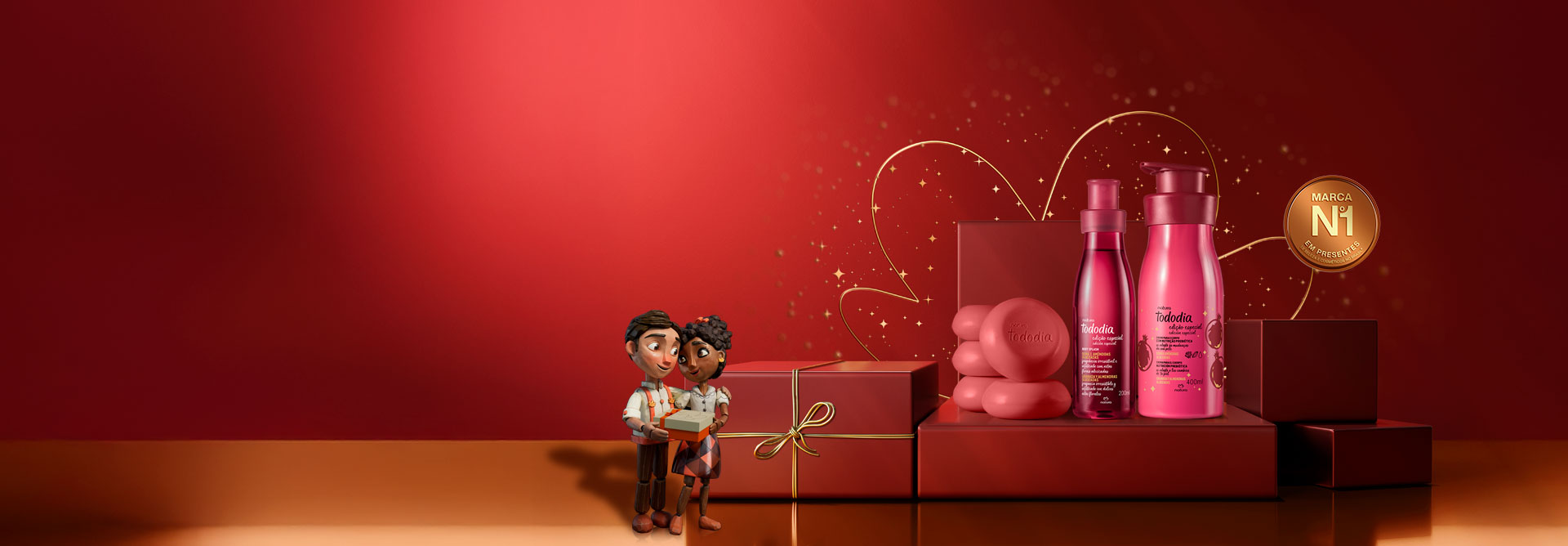 Fundo vermelho com detalhes e linhas douradas e selo onde é possível ler "Marca No 1 em Presentes". Do lado esquerdo, casal de bonecos de mdeira segurando presentes. Ao centro, sobre caixas de presente vermelhas, aparece uma sequência de Kits de Presentes da Natura.