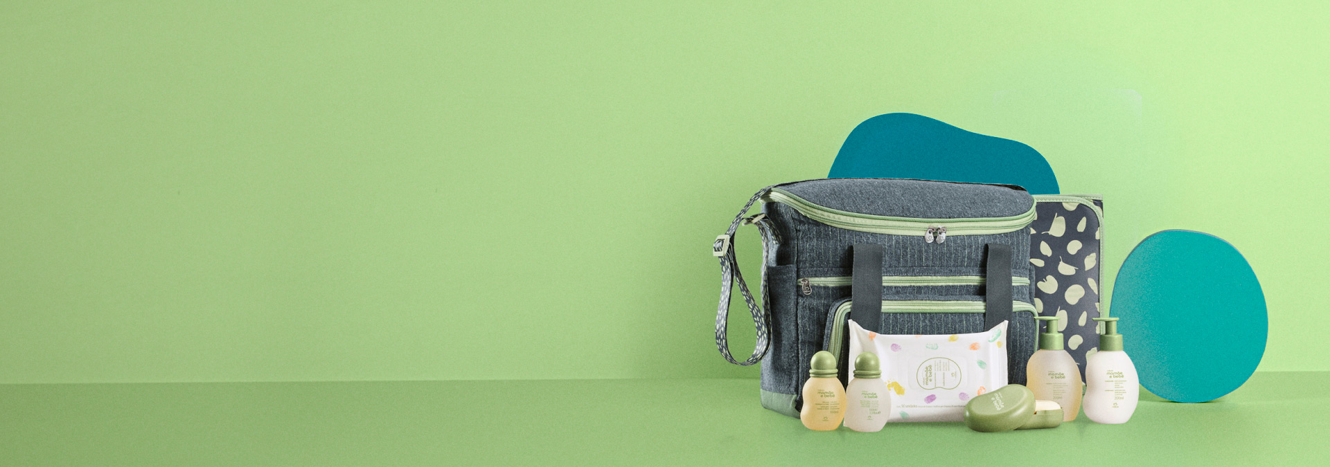 Fundo em tons de verde e ao lado direito o Conjunto Bolsa com Trocador Mamãe e Bebê