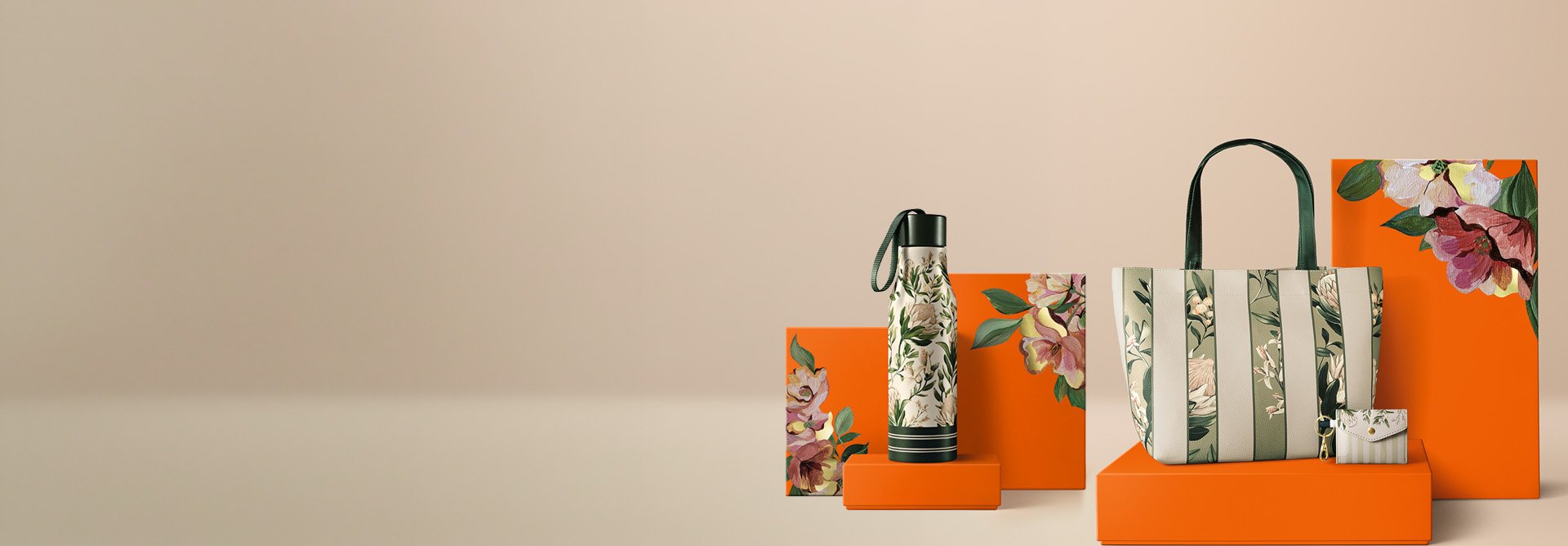 Itens Natura Crer Para Ver: Garrafa, Bolsa Listrada e Porta-Cartão, em verde floral sobre caixas laranja com ilustrações florais, em fundo bege.