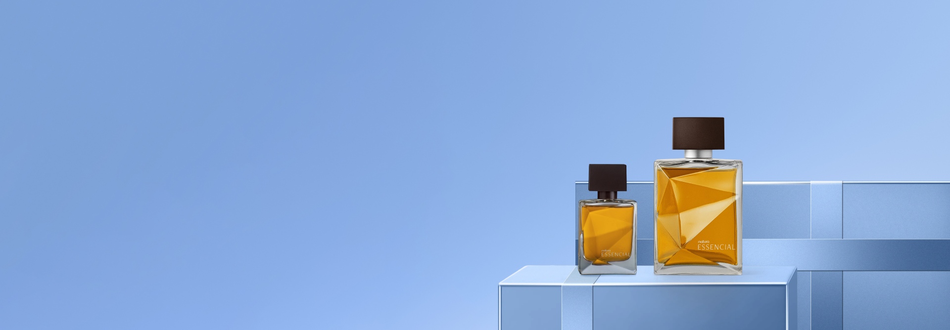 Dois frascos de Deo Parfum Essencial Masculino, um maior e outro menor, com líquido âmbar e tampas marrons escuras. Eles estão à direita sobre caixas de presente azuis claras em um fundo na mesma cor.