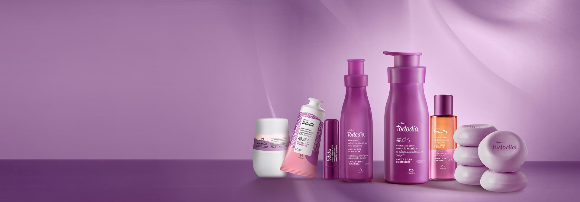 7 produtos de Tododia Ameixa e Flor de Baunilha: desodorante roll-on, balm labial, body splash, óleo bifásico, sabonetes em barra e cremes para o corpo e mãos. Embalagens roxas em fundo lilás.