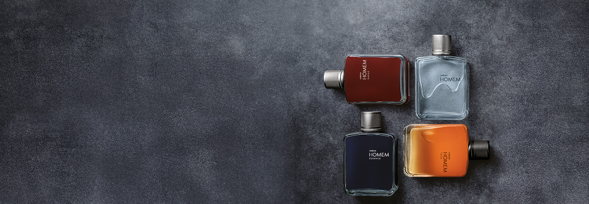 Frascos de 4 versões de Natura Homem em diferentes ângulos sobre fundo cinza. Natura Homem Sagaz na cor marrom, Natura Homem em azul-claro, Homem Tato em laranja e Homem Essence em azul escuro.