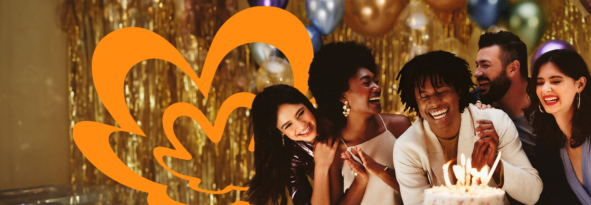 Pessoas sorriem e cantam parabéns para o aniversariante, que se prepara para soprar as velinhas de seu bolo de aniversário. Ao fundo, fitas e balões dourados e a rosácea da Natura em laranja.