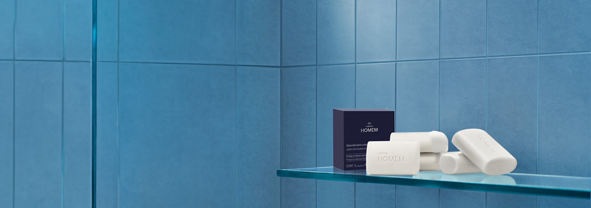 Fondo gris y blanco, y a la derecha una caja de jabón en barra Natura Hombre y tres jabones.