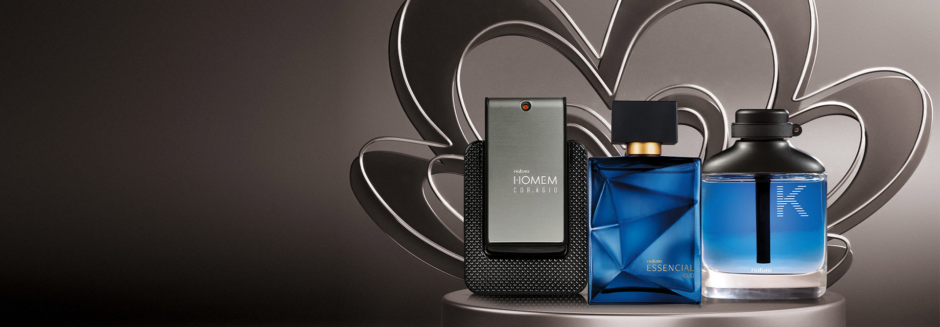 Tonos de gris al fondo con productos de la línea Natura Homem, Essencial, y Kaiak K, que representan la perfumería masculina.