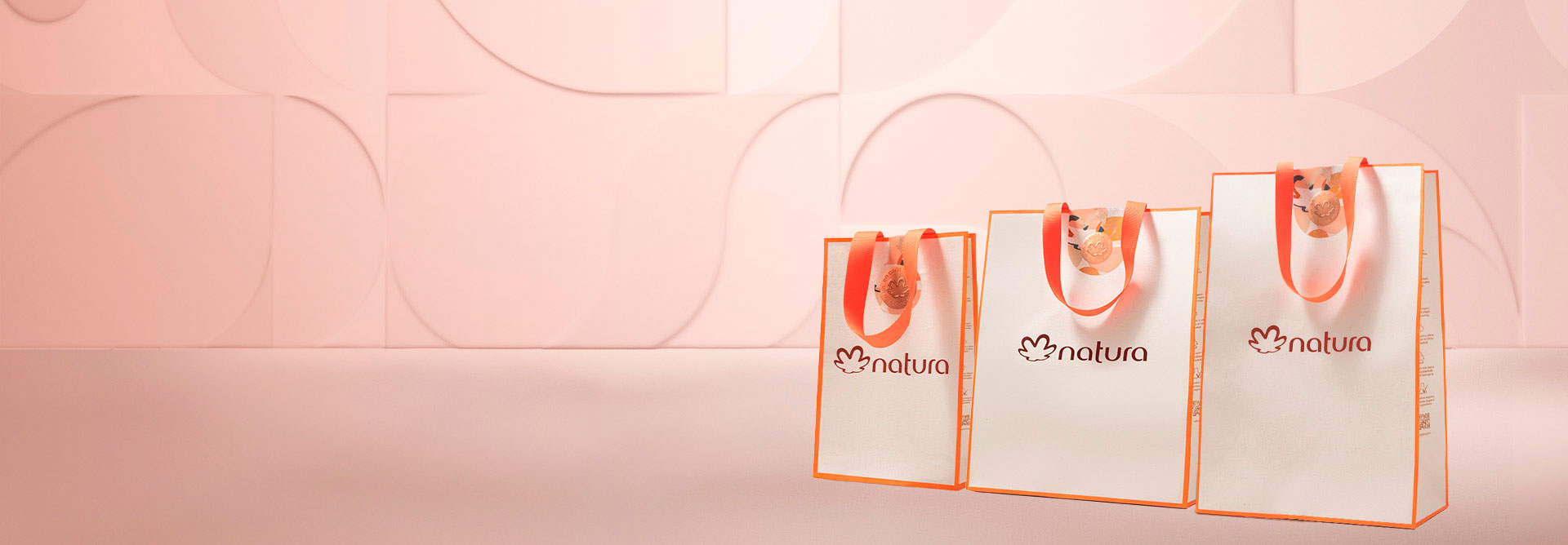 Fondo rosa y, al lado derecho de la imagen, tres bolsas de regalo de diferentes tamaños.