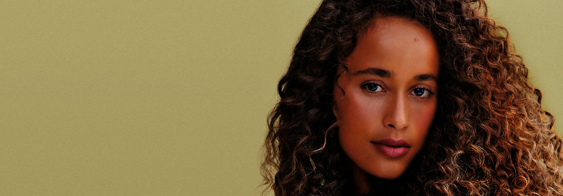 Fondo verde, al frente una mujer negra con cabello rizado.