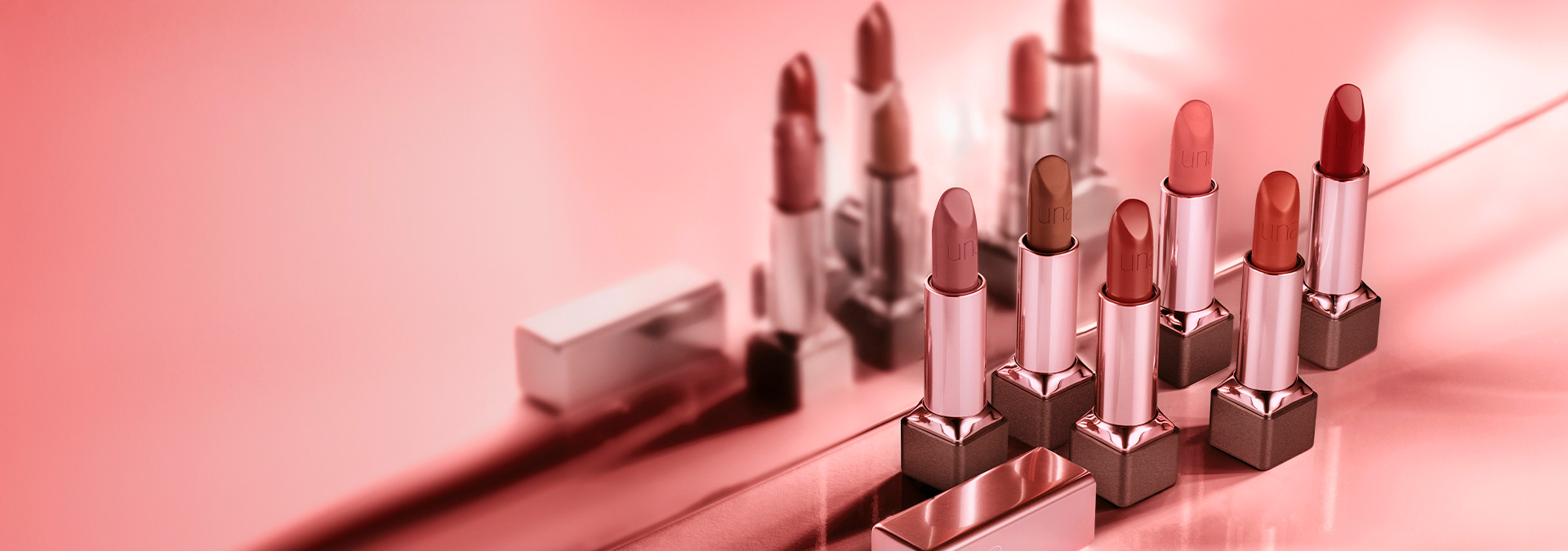 Imagen con fondo en tonos de rosa y a la derecha labiales Una de diferentes colores.​