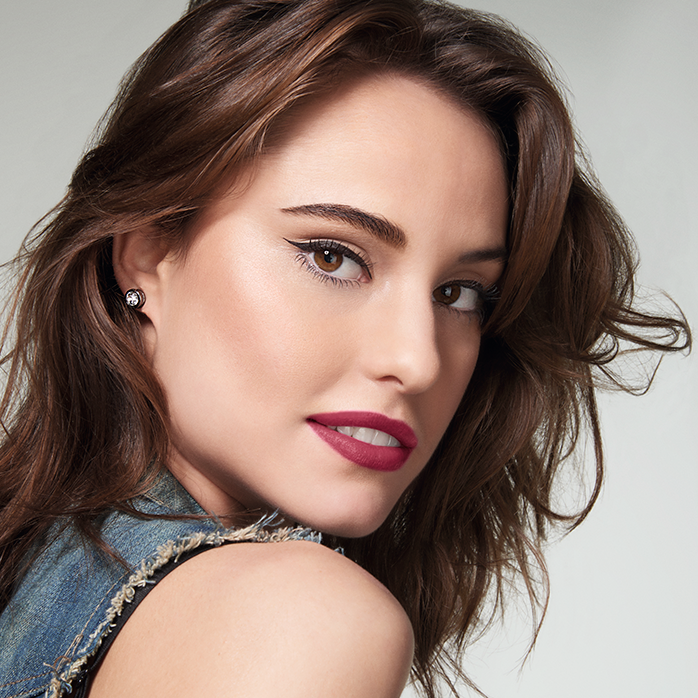 Modelo de piel clara, cabello castaño claro hasta los hombros, realzando los labios con un labial rojo oscuro.