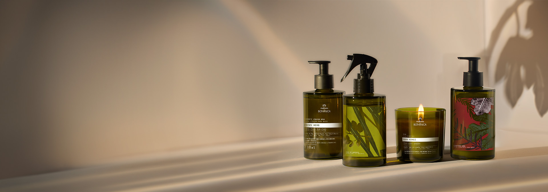 Cuatro frascos de productos Natura Bothanica en tonos verdes y marrones, alineadas sobre una superficie clara.