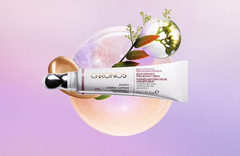 Sérum intensivo para bolsas y ojeras Chronos en un fondo unicolor y una flor.