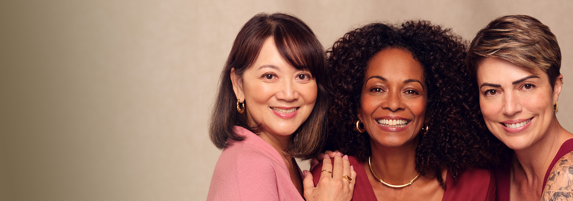 Tres mujeres de diferentes etnias y edades posan lado a lado, transmitiendo un mensaje de belleza diversa y atemporal.