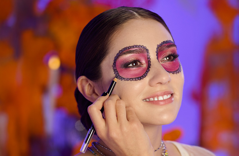 Mujer finalizando su maquillaje de Halloween de calavera con un lápiz