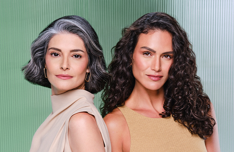 Dos mujeres. La de la izquierda tiene cabello gris corto y la de la derecha, cabello oscuro y rizado. Fondo verde con líneas verticales.