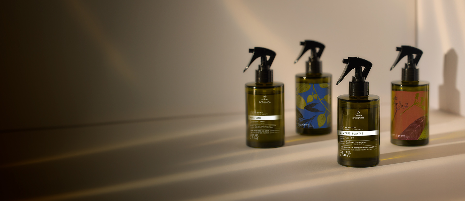 Cuatro frascos de productos Natura Bothanica en tonos verdes y marrones, alineadas sobre una superficie clara.