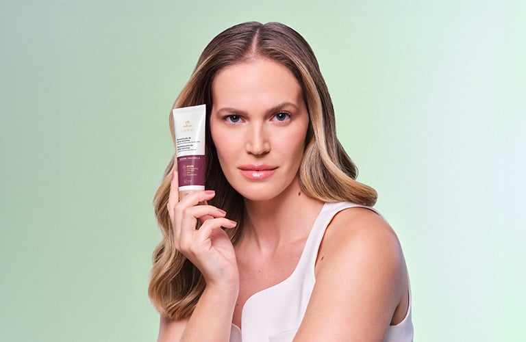 Modelo rubia sosteniendo la máscara reparadora de la línea Lumina para cabellos químicamente dañados