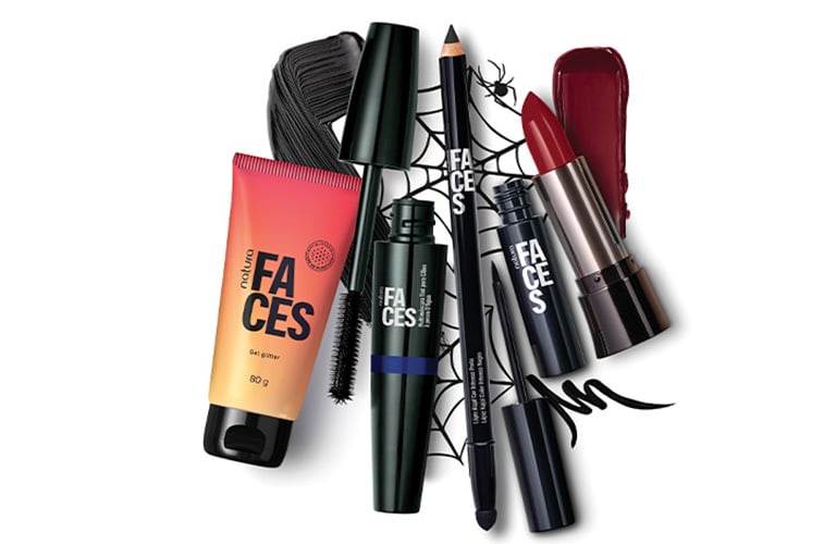 Foto con fondo blanco. Incluye productos de maquillaje: crema facial, lápices delineadores, máscara de pestañas, labial rojo, un peine negro y un diseño de telaraña en el centro.