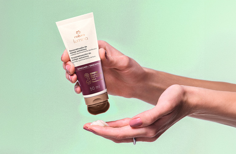 Una mano apretando una mascarillas para hidratar el cabello seco y maltratado y la otra agarrando el contenido