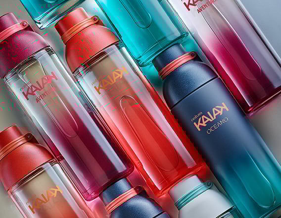 Frascos de Natura Kaiak en tonos de azul y rojo alineados sobre fondo claro, con los nombres de las fragancias visibles.