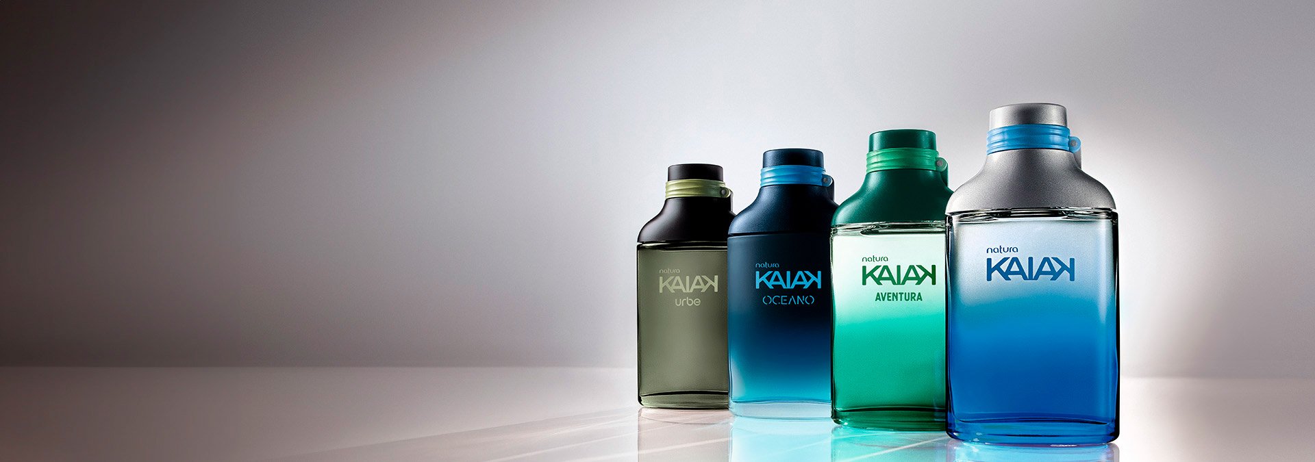 Frascos de perfume Kaiak en diferentes tonos de azul y verde, alineados sobre fondo blanco.