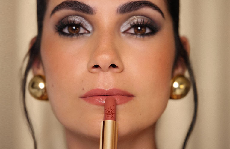 Modelo con maquillaje de gala, colocándose el labial Natura Una CC.