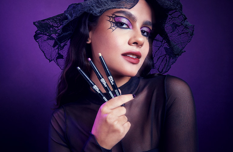 Foto con fondo rojo oscuro. Mujer con cabello recogido, accesorios dorados en la oreja derecha, maquillaje estilo vampiro con labios rojos intensos y ojos oscuros.