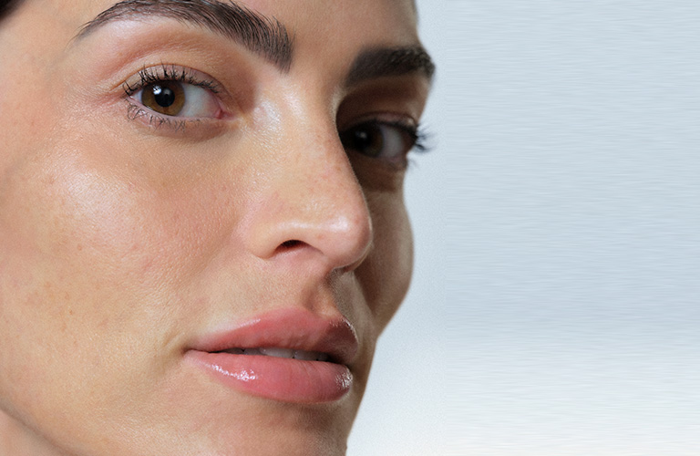 Foto en primer plano del perfil lateral de una persona con piel clara, mostrando su ojo marrón, ceja bien definida, nariz y labios, sobre un fondo claro.