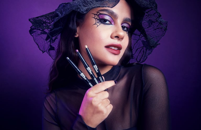 Foto con fondo púrpura oscuro. Mujer con sombrero negro de encaje y ropa negra translúcida, sosteniendo tres delineadores negros en su mano derecha. Imagen 06: Foto con fondo blanco. Incluye productos de maquillaje: crema facial, lápices delineadores, máscara de pestañas, labial rojo, un peine negro y un diseño de telaraña en el centro.